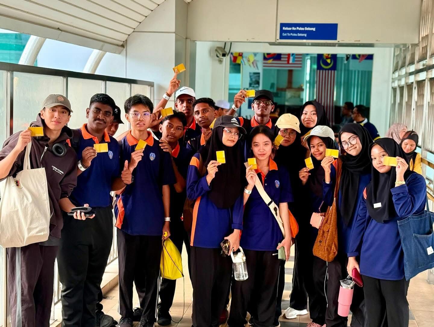 师生们在火车站高举免费乘车证，开心记录这趟前往A’Famosa 野生动物世界的美好旅程起点。