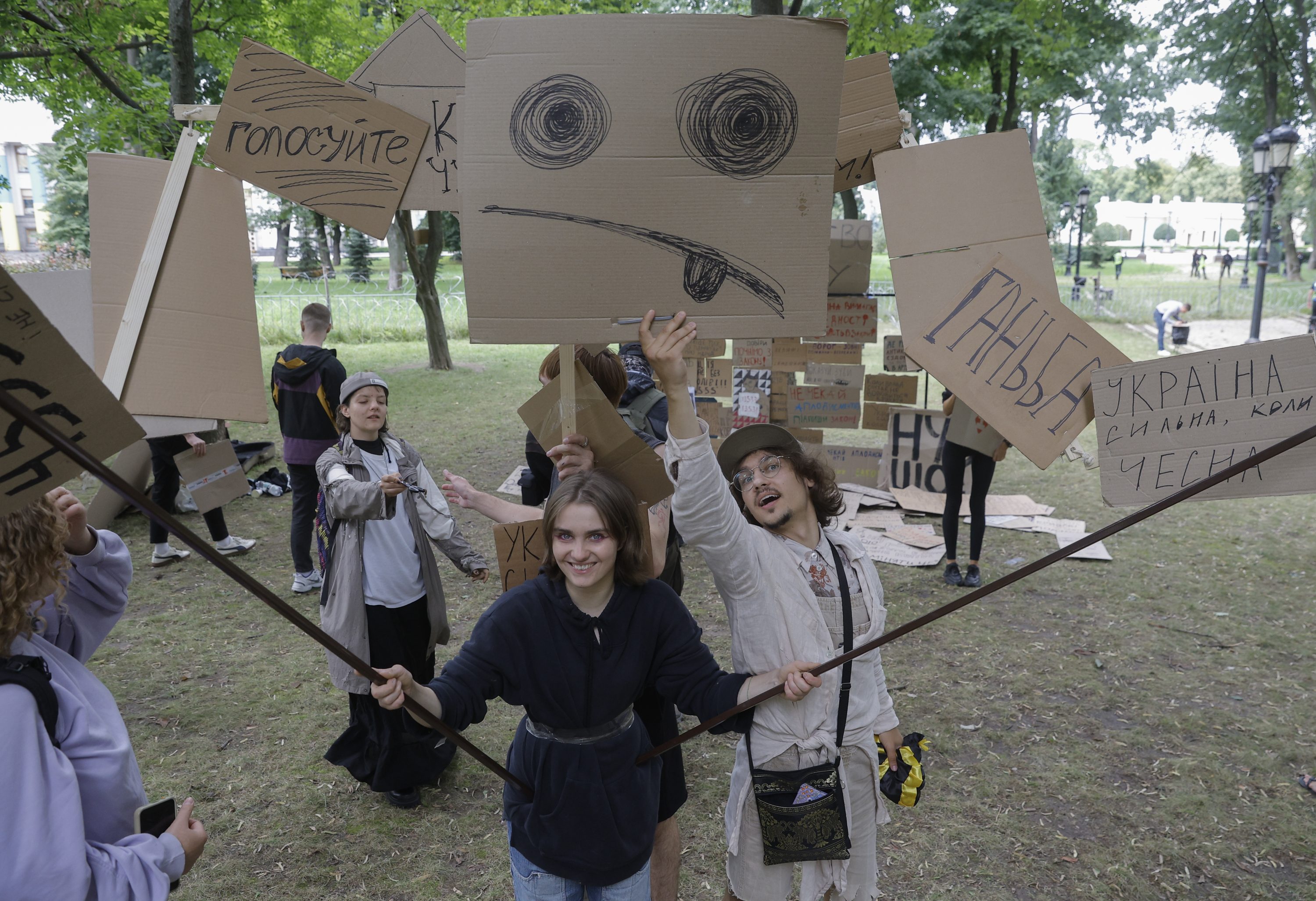 乌克兰民众在国会大厦附近手持绘有标语或图案的纸板,庆祝反贪机构的独立性得到维护。
