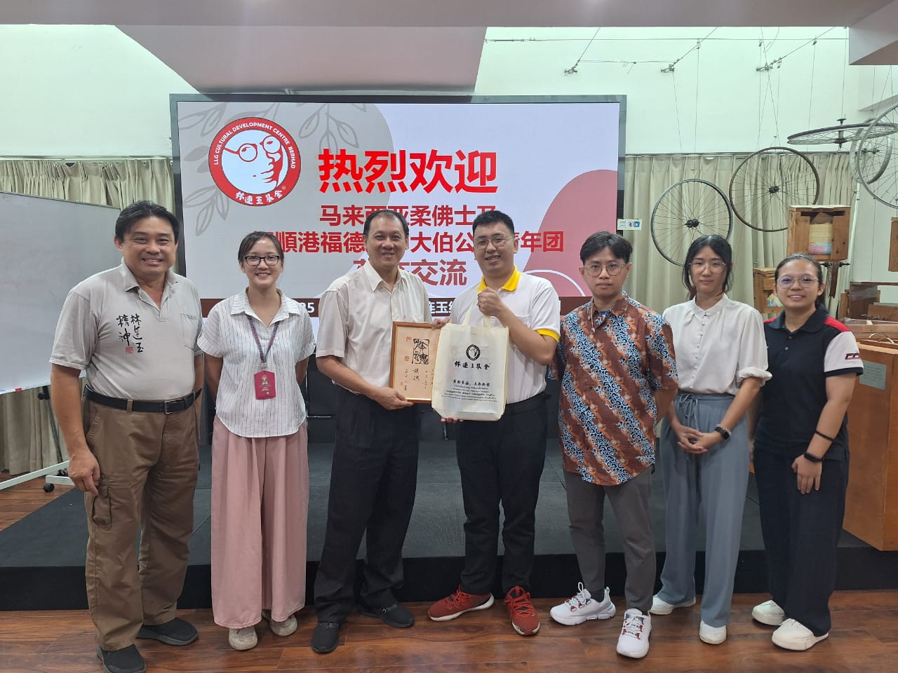 廖文辉(左三起)和柯福特交换纪念品。左起为林连玉基金副行政主任林嘉年、行政主任锺淑君、恒顺港大伯公庙副青年团长陈维浤、文艺局主任李佩颖和执委黄忻慈。