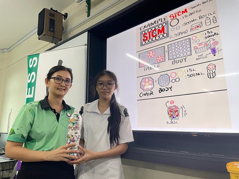 洪美鸾老师(左起)与陈真茹展示环保砖块,背后即是计划以砖块制成的“STCM”立板与桌椅设计图。