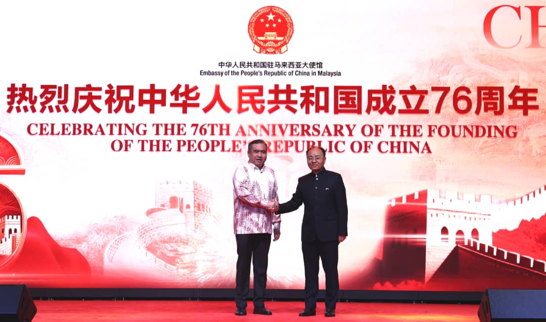 陆兆福(左)代表大马政府祝贺中国成立76周年。