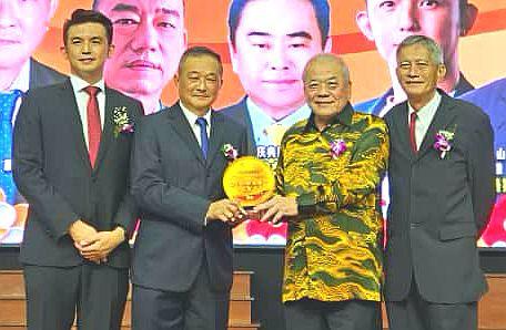 吴添泉（右二）从洪荣庆（左二）手中接过纪念盾。左为高秀荣，右为洪连海。